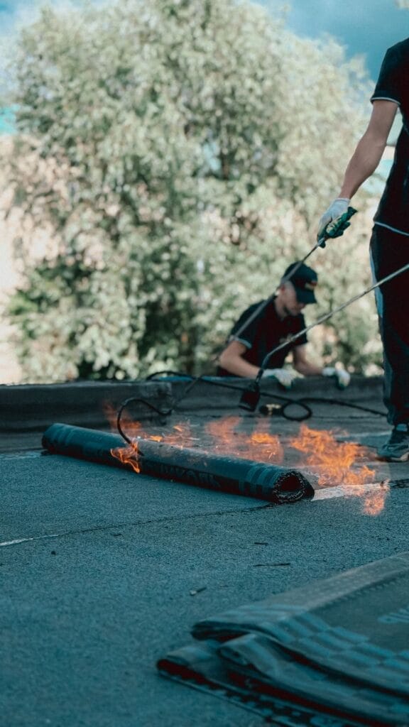 Roofers installing a torch-down modified bitumen roof